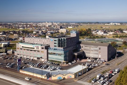 「広い駐車場に停めた車と施設外観」